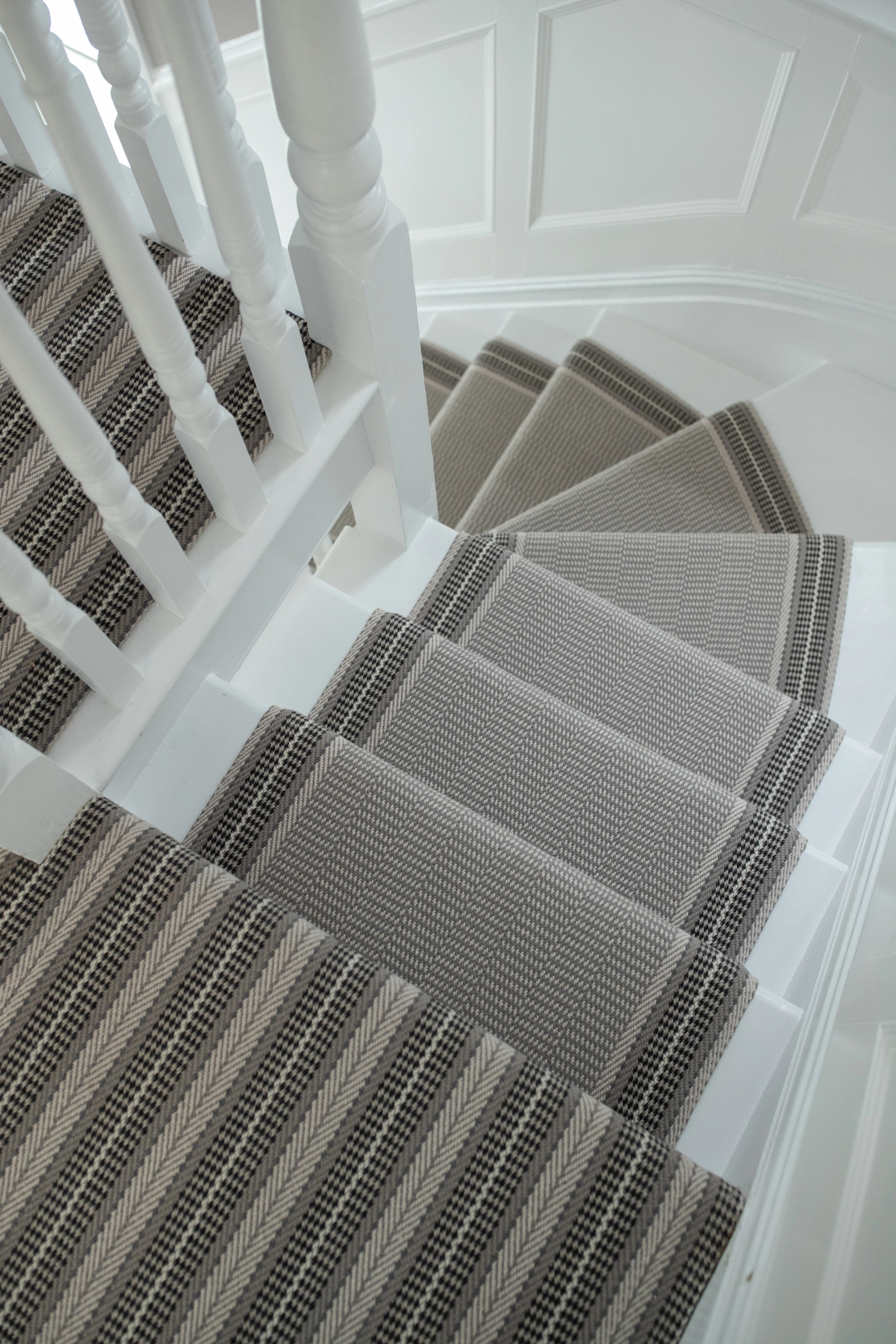 A Roger Oates brown and beige patterned carpet on a white staircase